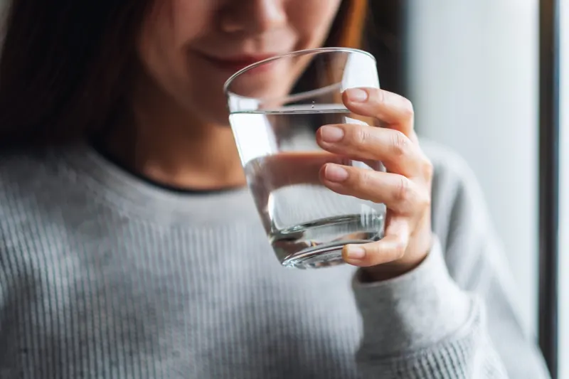 Una donna tiene in mano un bicchiere d'acqua